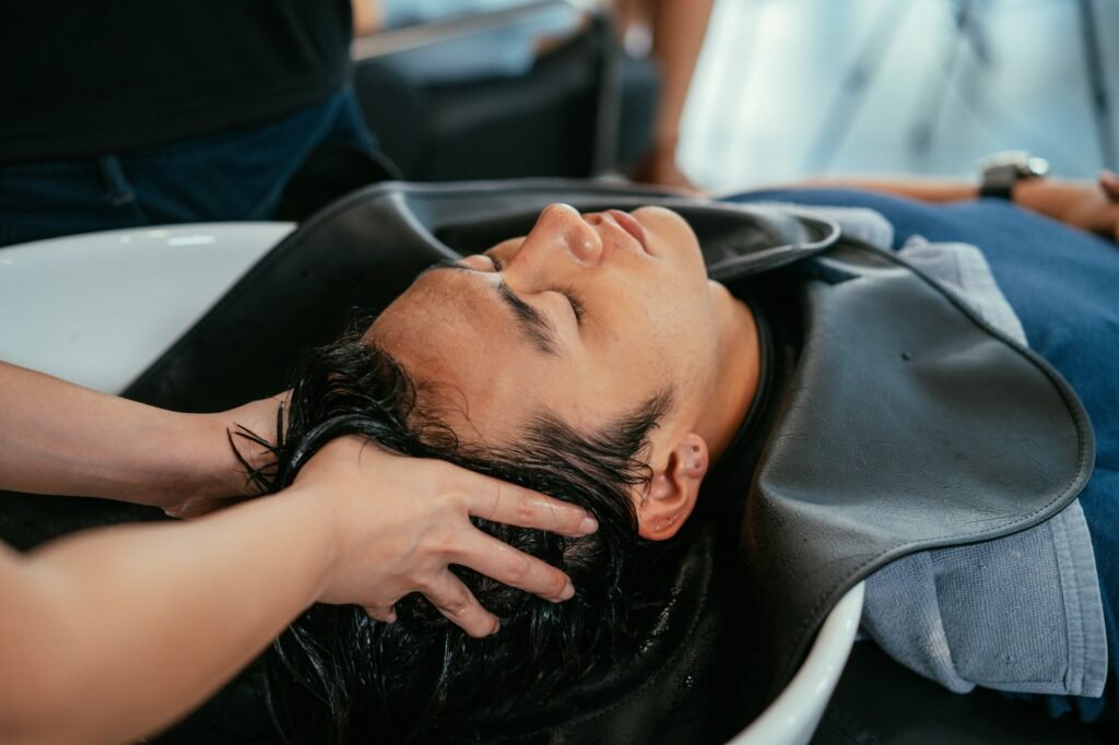 Barber washing head client in barbershop